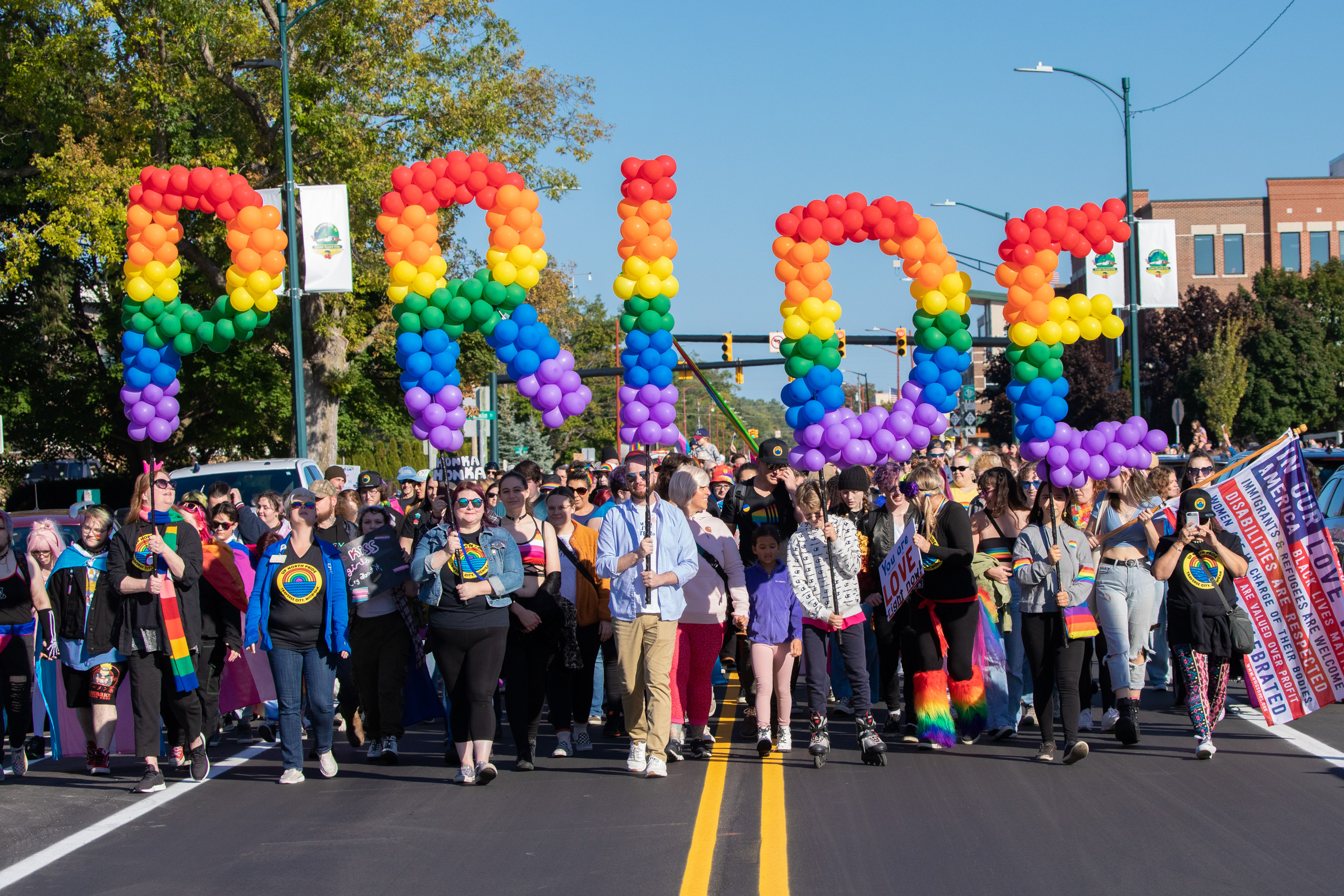 The very front of the Up North Pride parade, featuring people holding rainbow Pride balloons