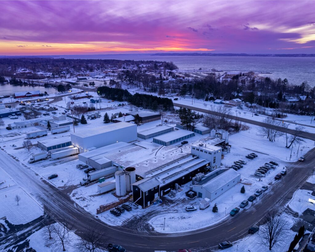 Aerial photo of the production facility in winter with Lake Michigan and a beautiful sunset in the background