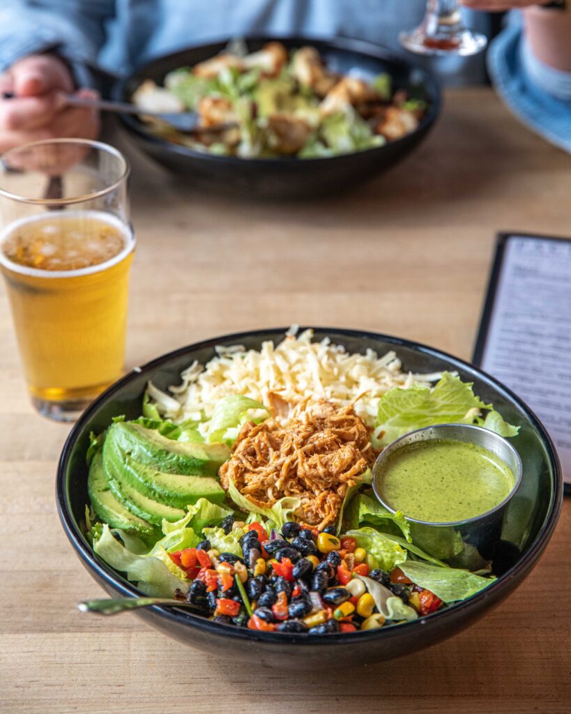 Photo of a giant salad with shredded chicken, black bean salsa, avocado, and cheese