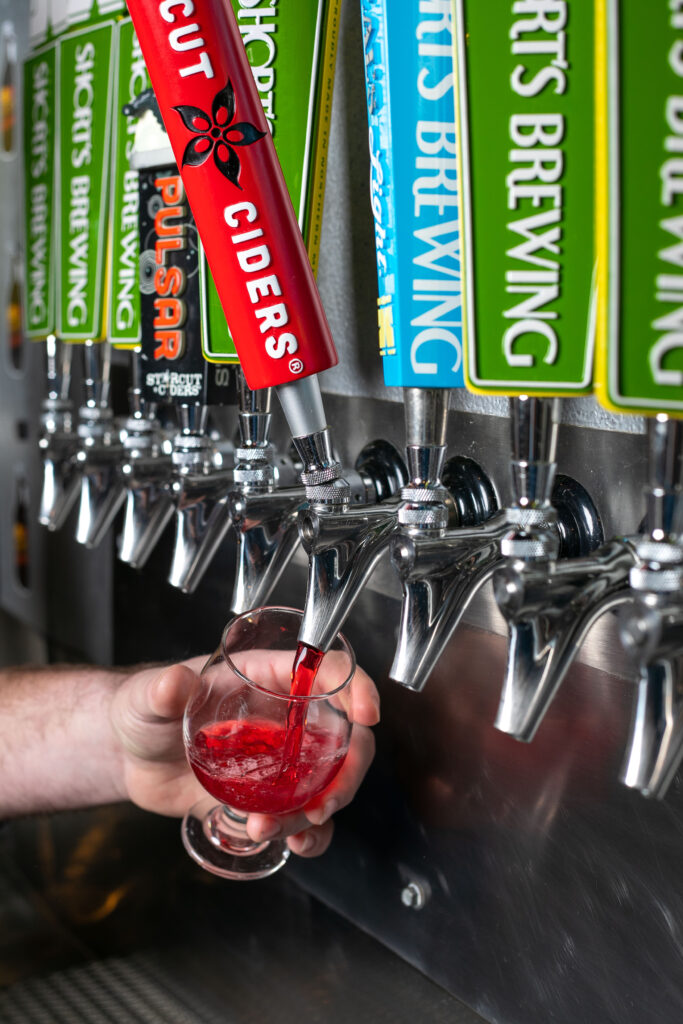 Photo of tap handles with a hand pouring a pink cider