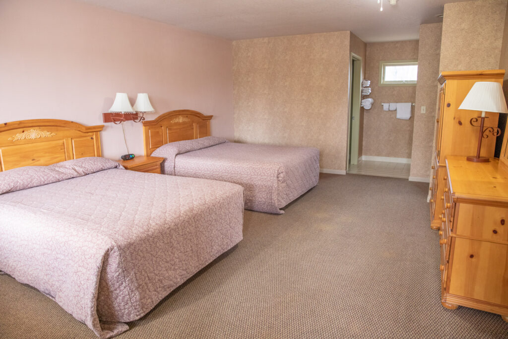 Photo showing clean, bright Inn room with two neatly-made beds for workforce housing.